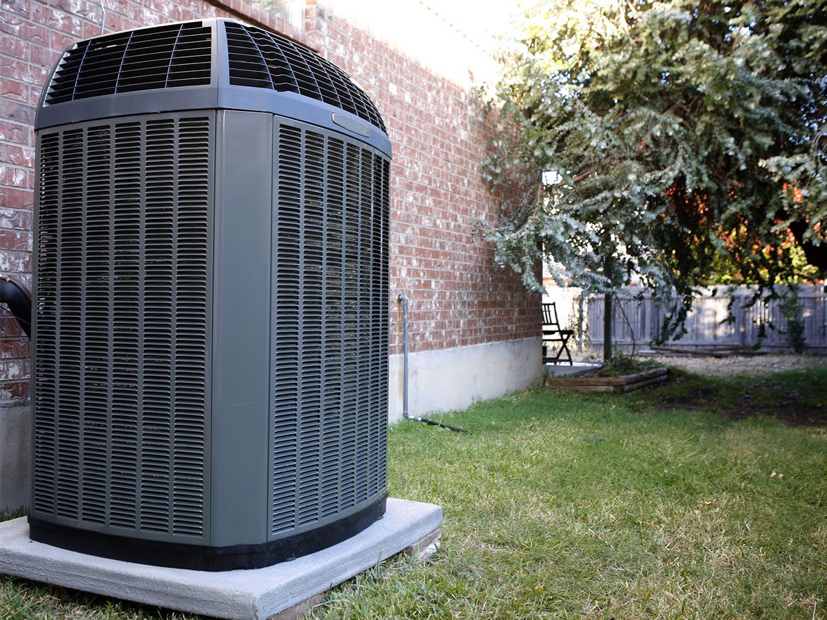 An outdoor air-conditioning condenser installed against a brick wall