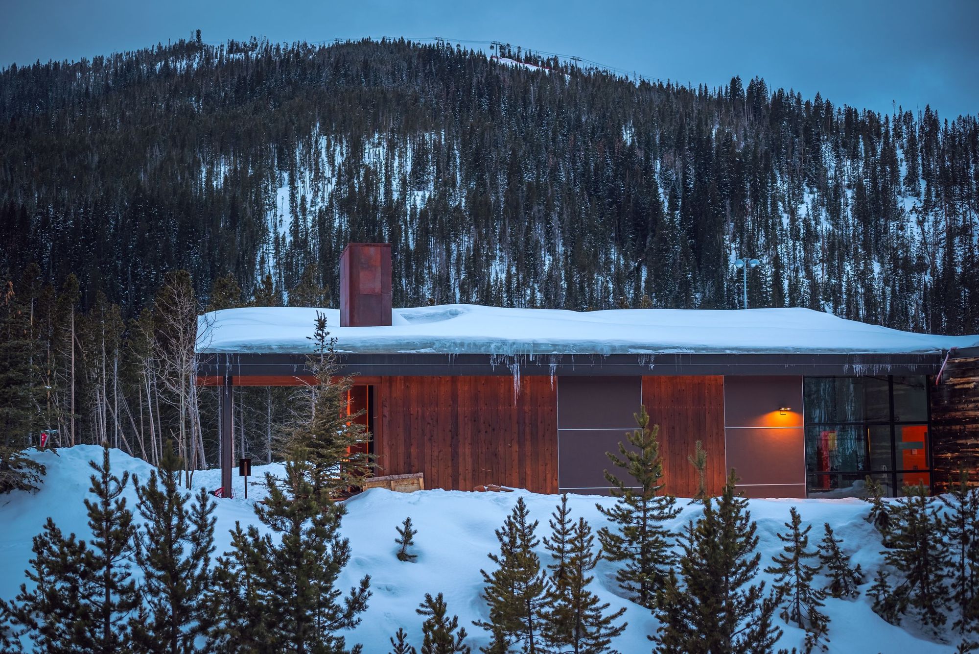 A snow-covered mountain cabin glowing at twilight